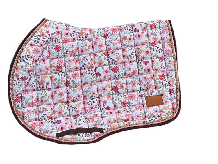 Blush floral jump saddle pad with brown trim on bench