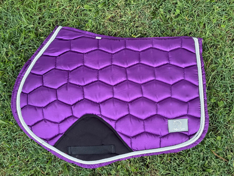 Purple honeycomb-quilted jump saddle pad with white trim on grass